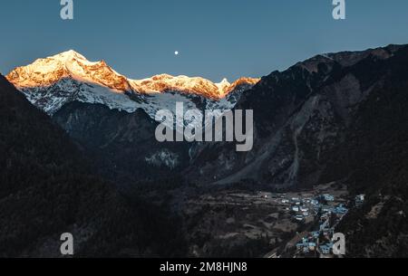 (230114) -- DEQEN, 14. Januar 2023 (Xinhua) -- Dieses Luftfoto wurde im Dorf Yubeng im Deqen County, Südwestchina, in der Provinz Yunnan aufgenommen und zeigt am 9. Januar 2023 Sonnenlicht auf dem Meili Snow Mountain. Wangden, 34, ist stellvertretender Direktor der Yunnan-Zweigstelle des Stromversorgungswerks Yanmen von China Southern Power Grid im Deqen County. 2015 wurde er beauftragt, Wartungsarbeiten in Yubeng zu übernehmen, einem Dorf am Fuße der schneebedeckten Berge. Als Yubengs dienstältester Energieversorger hat der Mann gewaltige Veränderungen im Dorf erlebt. In der Vergangenheit, Yube Stockfoto