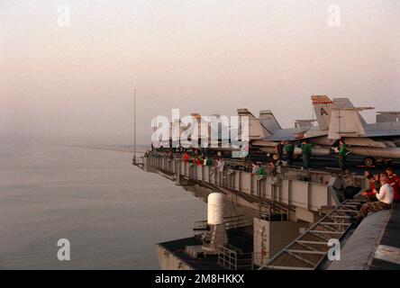 Hinter dem Flugzeug F/A-18 Hornet auf dem Cockpit des nukleargetriebenen Flugzeugträgers USS THEODORE ROOSEVELT (CVN-71) stehen Besatzungsmitglieder, die vom Geländer aus beobachten, wie das Schiff den Suezkanal auf dem Weg zum Roten Meer durchquert. Staat: Suez Canal Country: Ägypten (EGY) Stockfoto