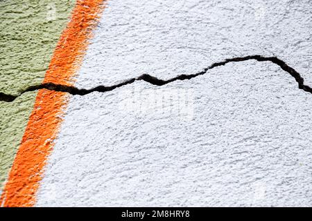 Großer Wicklungsriss an der alten mehrfarbigen Putzwand. Speicherplatz kopieren. Selektiver Fokus. Stockfoto
