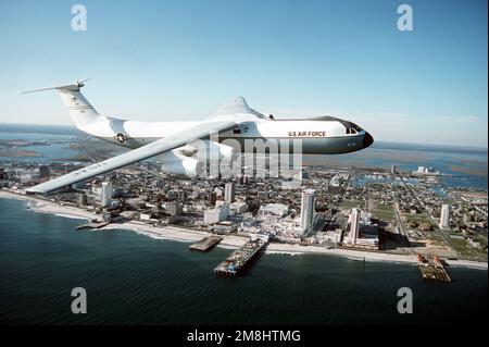 Eine Luft-zu-Luft-Seitenansicht eines 438. Airlift Wing, C-141 Starlifter, der über den Atlantik mit Atlantic City im Hintergrund fliegt. Der C-141, Hecknummer 70166, mit einem weiß lackierten Rumpf wird für den Transport leitender ziviler und militärischer Beamter verwendet. Exaktes Datum Aufnahme Unbekannt. Basis: Luftwaffenstützpunkt McGuire Bundesstaat: New Jersey (NJ) Land: Vereinigte Staaten von Amerika (USA) Stockfoto