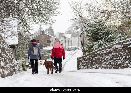 Spaziergänger mit einem Hund in Führung bei einem Spaziergang im Schnee in Hardrow in den Yorkshire Dales, Großbritannien Stockfoto