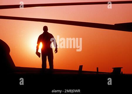 Ein Crewchef der Spezialeinheit 31. wird vom Sonnenuntergang umschlossen, als er auf einem MH-53J Pave Low III Hubschrauber steht, der zur Unterstützung des Fohlen Eagle '93 eingesetzt wurde. Einsatzgebiet/Serie: FOHLEN-ADLER '93 Stützpunkt: Taegu Luftwaffenstützpunkt Land: Korea Stockfoto