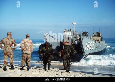 Mitglieder DER US-Armee beobachten, wie die US Navy Seabees vom Amphibien-Baubataillon 2, Norfolk, Virginia, bewaffnet mit M16 Gewehren und M60 Maschinengewehren von einem Landungsschiff (LCU 1663) an Land zu einem Strand in Ägypten ankommen, während der Übung BRIGHT STAR '94 stattfindet. Betreff Betrieb/Serie: BRIGHT STAR '94 Land: Ägypten (EGY) Stockfoto