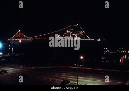 Ein Hafenblick bei Nacht auf das amphibische Sturmschiff USS KEARSAGE (LHD-3), das mit Weihnachtslichtern für die Weihnachtszeit ausgestattet ist, während es an der Nordseite von Pier neun gefesselt ist. Basis: Marine Air Station, Norfolk Bundesstaat: Virginia (VA) Land: Vereinigte Staaten von Amerika (USA) Stockfoto