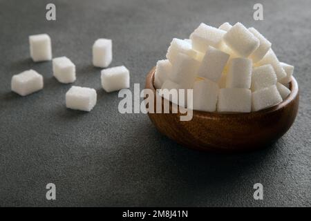 Weiße Zuckerwürfel in der Schüssel auf dunklem Hintergrund Stockfoto