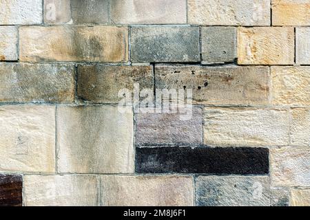 Ein Bruchteil einer alten Wand mit Steinblöcken zur Verwendung als abstrakter Hintergrund und Textur. Stockfoto