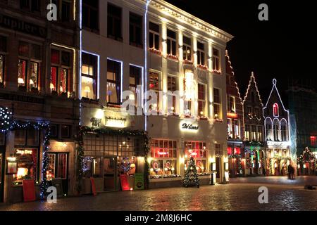 Weihnachtsdekorationen auf den Gebäuden rund um den Marktplatz, Brügge, Westflandern in der flämischen Region Belgiens. Stockfoto