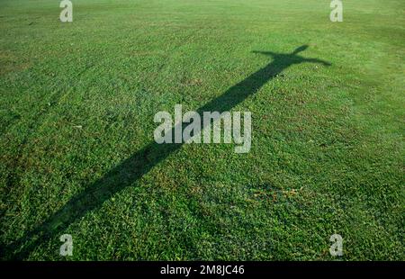 Silhouette des Menschen in Kreuzform auf grünem Gras Stockfoto