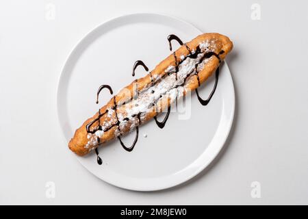 Gönnen Sie sich dazu gebratene Teigstäbchen auf weißem Teller Mekitsa oder Mekika, traditionelles serbisches bulgarisches und Makedoinan-Gericht aus Knete-Teig Stockfoto