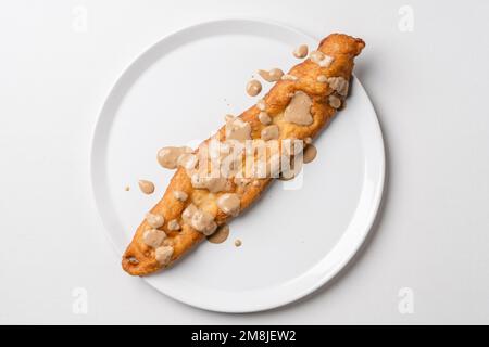 Gönnen Sie sich dazu gebratene Teigstäbchen auf weißem Teller Mekitsa oder Mekika, traditionelles serbisches bulgarisches und Makedoinan-Gericht aus Knete-Teig Stockfoto