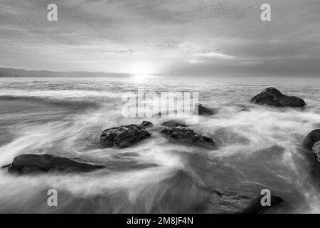 Nebiges Wasser Fließt Über Ocean Rocks Black And White Stockfoto