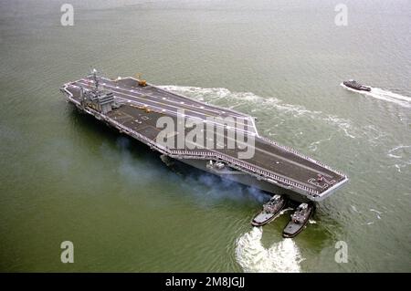 Steuerbord-Bogenansicht des nuklearbetriebenen Flugzeugträgers USS GEORGE WASHINGTON (CVN-73), der von zahlreichen Schleppbooten beim Abbiegen in den Kanal unterstützt wird, während das Schiff auf dem Weg zu ihrem Einsatz im Mittelmeer ist. Basis: Hampton Roadstead Bundesstaat: Virginia (VA) Land: Vereinigte Staaten von Amerika (USA) Stockfoto