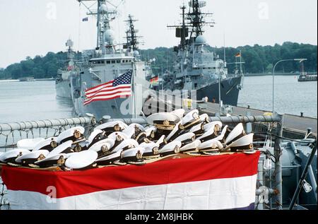 Offiziershüte aus vielen Ländern lagen auf einem Tisch auf dem Flugdeck des Zerstörers USS HAYER (DD-997). Offiziere aus 15 Nationen nahmen an einem Empfang an Bord des Schiffes Teil, der vom Kommandeur der Zerstörer-Staffel 14 (DesRon 14) während einer Pause von Aktivitäten auf See ausgerichtet wurde, um im Rahmen der Übung Baltic Operation '94 (BALTOPS 94) einen Hafenbesuch durchzuführen. Im Hintergrund stehen die Guided Missile Freggate USS OLIVER HAZARD PERRY (FFG-7), die russische Guided Missile Freggate NEUSTRASHIMYY und die deutschen Zerstörer MOLDERS (D-186) und LUETJENS (D-185). Betreff Betrieb/Serie: BALTOPS '94 Basis: Kiel Stockfoto