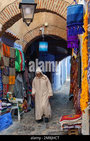 Nordafrika. Marokko. Chefchaouen. Ein alter Mann, gekleidet in einem Bournous, der in einer blauen Straße der Medina spaziert Stockfoto