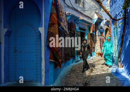 Nordafrika. Marokko. Chefchaouen. Eine Frau in Djelaba, die in einer blauen Straße der Medina spaziert Stockfoto