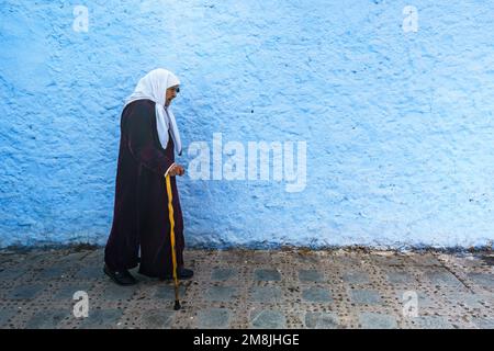 Nordafrika. Marokko. Chefchaouen. Eine alte Frau in Djellaba, die in einer blauen Straße der Medina spaziert Stockfoto