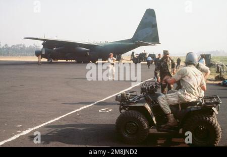 Ein C-130 Hercules vom 7. Sondereinsatzkommando (SOS), Alconbury, England, kommt am Flughafen Goma an, um Fracht zu liefern. Ein Soldat auf einem vierrädrigen Motorrad steht im Vordergrund. Betreff Operation/Serie: Support Hope Base: Goma Country: Zaire (ZAR) Stockfoto