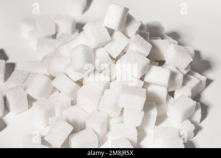 Raffinierte Zuckerwürfel blockieren Stücke im Stapel und Haufen. Überkonsum von zuckerhaltigen Produkten, ungesunde Ernährung Konzept. Hochwertiges Foto Stockfoto