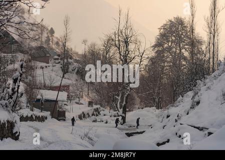 Srinagar, Indien. 14. Januar 2023. Die Bewohner wandern bei Sonnenuntergang entlang einer schneebedeckten Brücke nach einem schweren Schneefall in den Außenbezirken von Srinagar. Am Samstag wurden Lawinen in den Bezirken Bandipora (Gurez) und Ganderbal (Sonamarg) in Jammu und Kaschmir gemeldet, die in den letzten Tagen schwere Schneefälle erlebt haben. Die Lawine in Sonamarg ist die zweite in zwei Tagen. (Foto: Idrees Abbas/SOPA Images/Sipa USA) Guthaben: SIPA USA/Alamy Live News Stockfoto