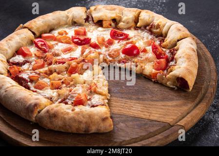 Pizza Margherita auf schwarzem Steinhintergrund. Pizza für Gesellschaft. Eine Scheibe fehlt Stockfoto