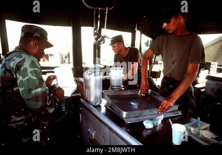 SGT. 1. Uhr Klasse Tomas Delgadillo, PVT. 2 Brandy Walley und PFC Shawn Gibbs von The Headquarters and Headquarters Company (HHC) 7. Bataillon 1. Brigade, 3. Infanterieabteilung, Katterbach, Deutschland bereiten sich darauf vor, Mahlzeiten an US-Militärangehörige zu servieren, die am Flughafen eingesetzt werden. Betreff Betrieb/Serie: SUPPORT HOPE Base: Kigali Airport Land: Russland (RUS) Stockfoto