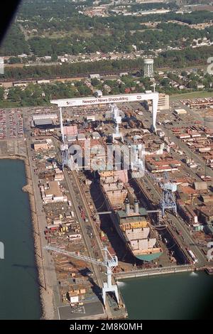 Drydock #12 der Newport News Shipbuilding & Drydock Corporation am James River aus der Vogelperspektive. Vor dem Dock befindet sich das neue Fahrzeug-Transportschiff GORDON (T-AKR-296) des militärischen Sealift-Kommandos. Im hinteren Teil des Docks befindet sich der modulare Mitschiffsabschnitt des nuklearbetriebenen Flugzeugträgers United States (CVN-75), der im Bau ist. Basis: Newport News Bundesstaat: Virginia (VA) Land: Vereinigte Staaten von Amerika (USA) Stockfoto