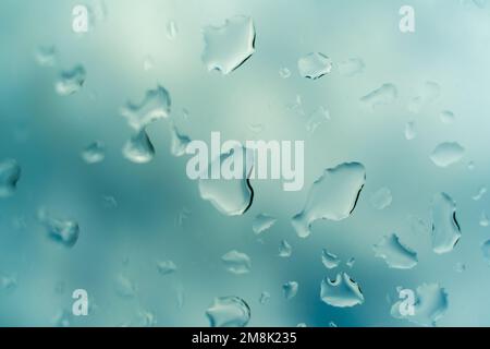 Wassertropfen auf Glas vor blauem Himmel, Regenzeit-Konzept. Fensteransicht Hintergrund Bildschirmschoner Stockfoto