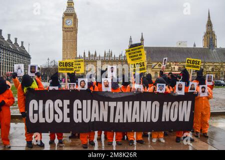 London, England, Großbritannien. 14. Januar 2023. Demonstranten mit Kapuzen über ihren Köpfen halten Bilder von Guantanamo-Gefangenen und ein Banner auf dem Parliament Square. Aktivisten in orangefarbenen Gefängnisanzügen marschierten durch Westminster und forderten die Schließung des Gefangenenlagers Guantanamo Bay. Im Januar 11. jährt sich der 21. Jahrestag seit der Eröffnung des umstrittenen Gefängnisses. (Kreditbild: © Vuk Valcic/ZUMA Press Wire) NUR REDAKTIONELLE VERWENDUNG! Nicht für den kommerziellen GEBRAUCH! Kredit: ZUMA Press, Inc./Alamy Live News Stockfoto