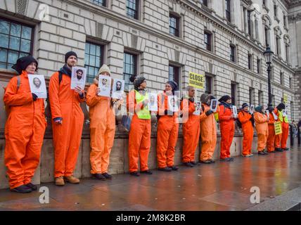 London, England, Großbritannien. 14. Januar 2023. Demonstranten halten Fotos von Guantanamo-Gefangenen auf dem Parlamentsplatz. Aktivisten in orangefarbenen Gefängnisanzügen marschierten durch Westminster und forderten die Schließung des Gefangenenlagers Guantanamo Bay. Im Januar 11. jährt sich der 21. Jahrestag seit der Eröffnung des umstrittenen Gefängnisses. (Kreditbild: © Vuk Valcic/ZUMA Press Wire) NUR REDAKTIONELLE VERWENDUNG! Nicht für den kommerziellen GEBRAUCH! Kredit: ZUMA Press, Inc./Alamy Live News Stockfoto