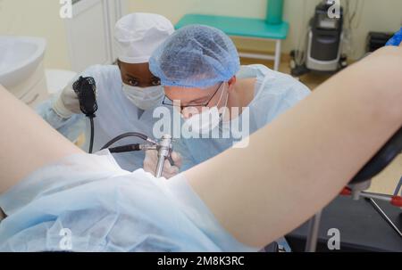 Ein männlicher Arzt führt eine Darmspiegelung durch und untersucht das Rektum eines Patienten, der auf dem Operationstisch liegt. Stockfoto