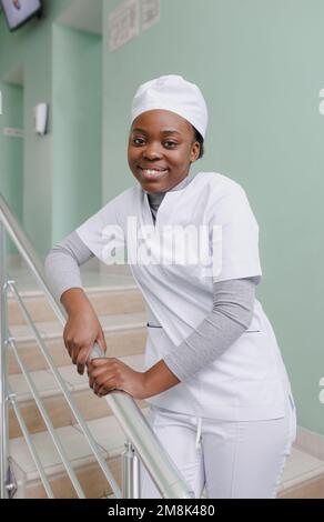 Lächelnde afroamerikanische Krankenschwester stand während der Coronavirus-Pandemie Covid 19 auf der Treppe Stockfoto