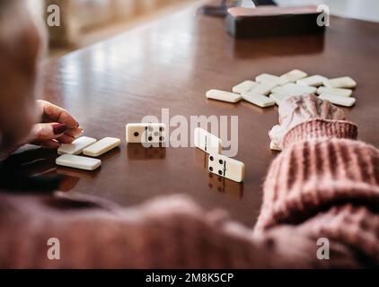 Rückansicht einer älteren Person, die Dominosteine spielt. Spaßbegriff und Alter. Selektive Weichzeichnung. Stockfoto