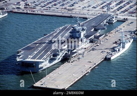 Ein Steuerbord-Viertelblick eines nuklearbetriebenen Flugzeugträgers USS ENTERPRISE (CVN-65), der an der Nordseite von Pier 11 befestigt ist. Die kanadische Fregatte HMCS TERRA NOVA (DDE-259) macht einen Hafenbesuch und ist auf der Südseite gefesselt. Basis: Hampton Roadstead Bundesstaat: Virginia (VA) Land: Vereinigte Staaten von Amerika (USA) Stockfoto