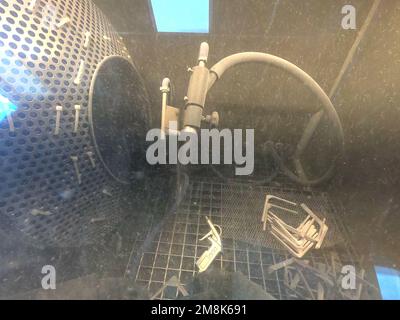 Schusssprengen. Sprengung des Modells auf 3D-Drucker aus Polyamidpulver. Ein Arbeiter in versiegelten Gummihandschuhen reinigt den Gegenstand durch Schusssprengen in einer Schusssprengring-Kammer. Industriemaschinen Stockfoto