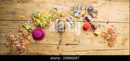 Karneval-Donuts aus Deutschland mit Puderzucker auf einer hellen Holzfläche mit Konfetti und Luftschlangen - Hintergrund für eine Karnevalsparty oder -Partys Stockfoto
