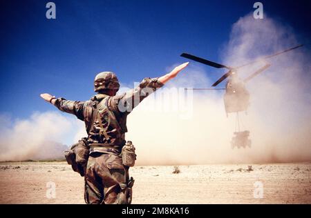 SERGEANT David Mullins, Bravo Company, 12. Air Defense Artillery, Ft. Polk, Louisiana, marschiert einen CH-53 Chinook mit einer Avenger-Einheit, die sich dem Einführungspunkt am Condron Army Air Field nähert. Die Avenger-Einheit ist ein Mehrzweckfahrzeug mit Mobilitätshilfen (HMMWV) und einem am Revolver montierten Stinger Starter-Modul. Der Chinook wird zuerst den Avenger auf den Boden bringen und das Seil lösen, dann landet er neben ihm, um den Schutz der Streitkräfte und das Avenger-Personal zu entladen. Betreff: ROVING SANDS '95 Base: White Sands Missile Test Range State: Ne Stockfoto