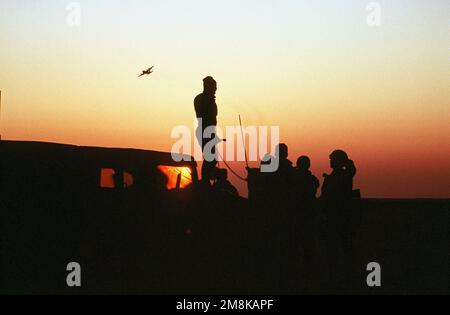 Eine Silhouette von einigen Mitgliedern der 82. Luftwaffe, Fort Bragg, NC, beobachten den Sonnenuntergang, während ein Flugzeug über die Luft fliegt, bevor es seine Ladung Fallschirmjäger in der Holland Drop Zone entlädt. Betreff Betrieb/Serie: BIG DROP II Basis: Fort Bragg Bundesstaat: North Carolina (NC) Land: Vereinigte Staaten von Amerika (USA) Stockfoto