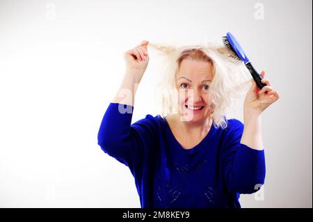 Friseurmedizin Haarrestauration beschädigte Haare mit gespaltenen Enden übergetrocknet verzogene Erwachsene Frau blond färben weiß beschädigte traurige Frau mit geschwollenem C Stockfoto