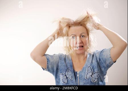 Friseurmedizin Haarrestauration beschädigte Haare mit gespaltenen Enden übergetrocknet verzogene Erwachsene Frau blond färben weiß beschädigte traurige Frau mit geschwollenem C Stockfoto