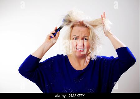 Friseurmedizin Haarrestauration beschädigte Haare mit gespaltenen Enden übergetrocknet verzogene Erwachsene Frau blond färben weiß beschädigte traurige Frau mit geschwollenem C Stockfoto