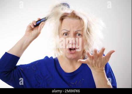 Friseurmedizin Haarrestauration beschädigte Haare mit gespaltenen Enden übergetrocknet verzogene Erwachsene Frau blond färben weiß beschädigte traurige Frau mit geschwollenem C Stockfoto