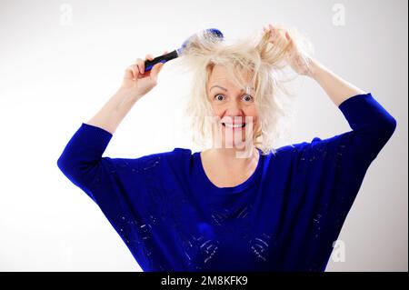 Friseurmedizin Haarrestauration beschädigte Haare mit gespaltenen Enden übergetrocknet verzogene Erwachsene Frau blond färben weiß beschädigte traurige Frau mit geschwollenem C Stockfoto