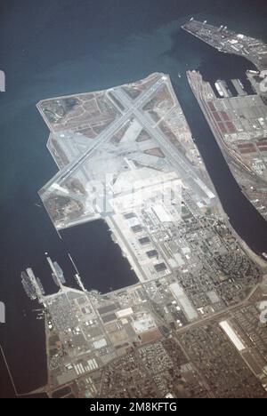 Von oben schräge Luftaufnahme des Marineflugbahnhofs Alameda mit Blick nach Westen (vertikales Format), mit Blick auf den Flugplatz und den Flugzeugträger-Pier-Komplex, in dem die pazifischen Oberflächenkräfte untergebracht sind. Der Flugzeugträger USS Kitty Hawk (CV-63) ist links angebunden. Der ehemalige Unterwasserschutzträger Hornet (CVS-12) der Essex-Klasse ist auf der rechten Seite verankert. Die Hornet wurde aus dem Marineregister gelöscht und wird bald abgeschafft. Basis: Alameda Staat: Kalifornien (CA) Land: Vereinigte Staaten von Amerika (USA) Stockfoto