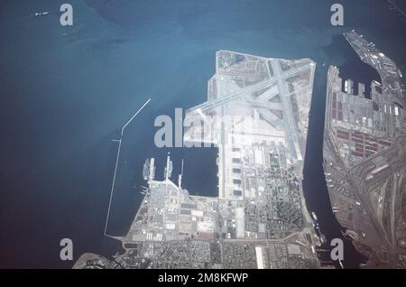 Luftaufnahme der Naval Air Station Alameda (horizontales Format) von oben, die den Flugplatz und den Flugzeugträger-Pier-Komplex mit pazifischen Oberflächenkräften zeigt. Der Flugzeugträger USS Kitty Hawk (CV-63) ist links verankert. Der ehemalige Unterwasserschutzträger Hornet (CVS-12) der Essex-Klasse ist rechts verankert. Die Hornet wurde aus dem Marineregister gelöscht und wird bald abgeschafft. Basis: Alameda Staat: Kalifornien (CA) Land: Vereinigte Staaten von Amerika (USA) Stockfoto