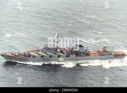 Seitlicher Blick vom Lufthafen auf den Raketenkreuzer Varyag (CG-011) der russischen Marine Pacific Fleet der Slava-Klasse im Gange. Das Schiff hieß früher Chernova Ukraina. Beachten Sie, dass der Name der Heckplatte noch nicht geändert wurde. Land: Meer Von Okhotsk Stockfoto