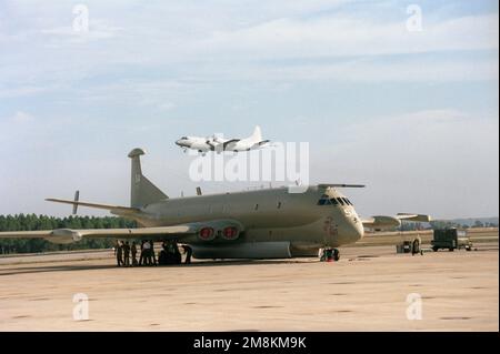 Auf der Rollbahn sitzt ein Nimrod-Aufklärungs- und Patrouillenflugzeug der britischen Royal Navy. Das 120. CSX-Geschwader, RAF Kinloss, England, hat eine 4-Flugzeug-Einheit in Jacksonville. Im Hintergrund nähert sich ein P-3C Orion-Flugzeug zur Landung. Basis: Marineflugstation, Jacksonville Bundesstaat: Florida (FL) Land: Vereinigte Staaten von Amerika (USA) Stockfoto