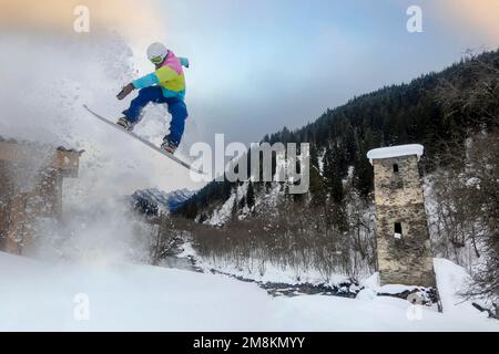 Ein Snowboarder springt über den historischen Svan Tower in Mestia, Georgia, Love Tower Stockfoto