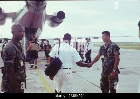US Army PFC Ravera (rechts) und SPC Keller (links) schütteln den kubanischen Migranten die Hand, wenn sie an der US Naval Base Guantanamo Bay, Kuba, für einen Flug in die USA an Bord eines Flugzeugs gehen. Basis: Guantanamo Bay Country: Kuba (CUB) Stockfoto