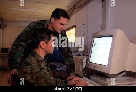 United States Forces Japan (USFJ) Army MAJ Daniel Baggio beobachtet die JGSDF LTD COL Seijiro Kiyomichi (Japan Ground Self Defense Force), die Aktionen überwacht, während sie das JTLS-System (Joint Theater Level Simulation) am Luftwaffenstützpunkt Yokota, Japan, testet. Mitglieder des USFJ und der JSDF führen vom 25. Januar bis zum 2. Februar 1996 eine gemeinsame/bilaterale Kommandostationsübung Keen Edge '96 in US-amerikanischen und japanischen Militäreinrichtungen durch. Betreff Operation/Serie: KEEN EDGE '96 Land: Unbekannt Stockfoto