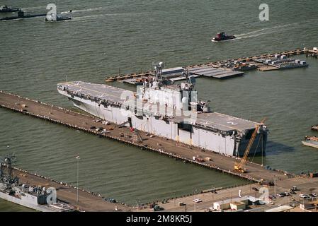 Lufthafenviertelblick auf das amphibische Sturmschiff USS Saipan (LHA-2) an der Nordseite von Pier 6. Oben links auf dem Foto ist ein nuklearbetriebenes Angriffs-U-Boot der Los Angeles-Klasse, das in Begleitung von zwei YTBs ankommt. Basis: Marine Air Station, Norfolk Bundesstaat: Virginia (VA) Land: Vereinigte Staaten von Amerika (USA) Stockfoto